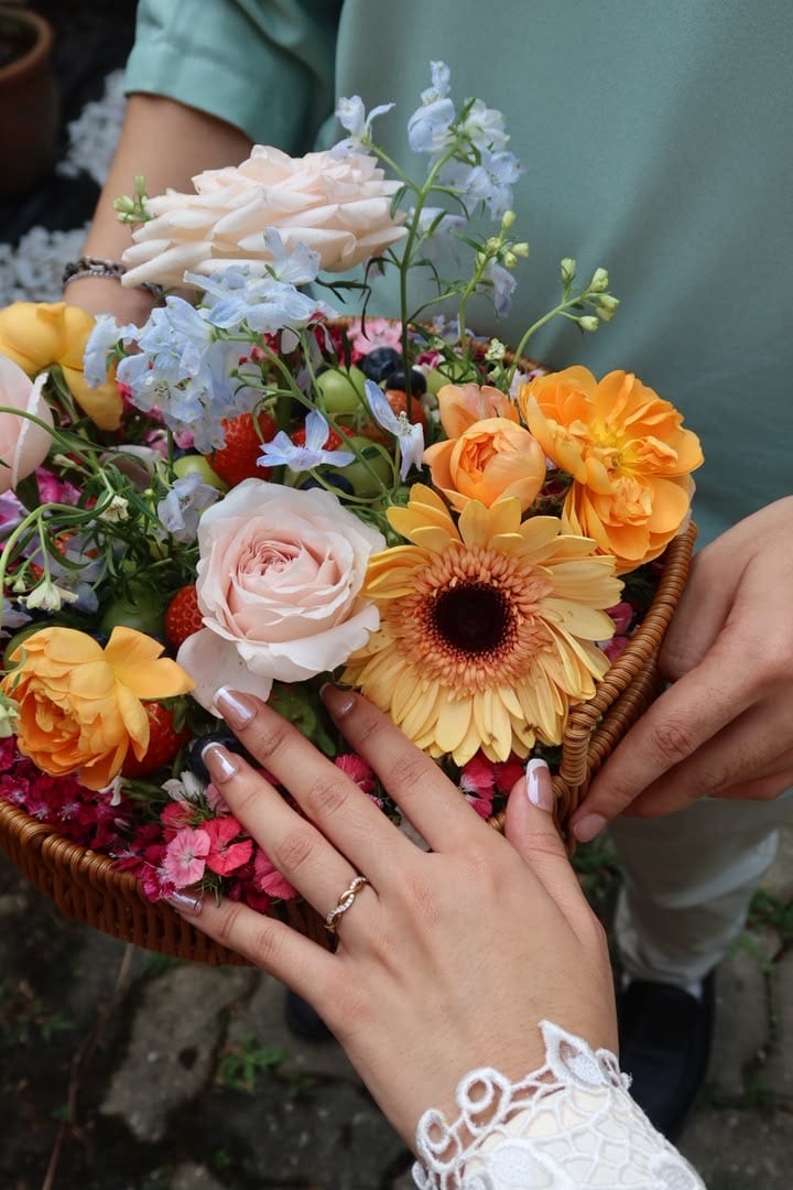 The couple’s hands over the flower basket, engagement ring on show